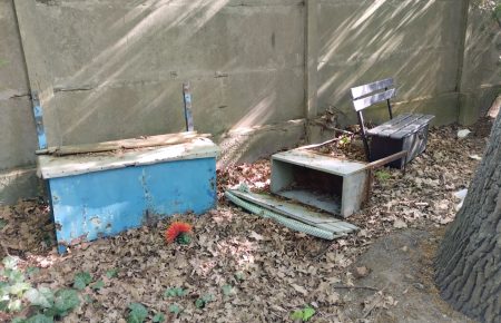 Stare uszkodzone ławeczki porzucone pod ogrodzeniem cmentarza